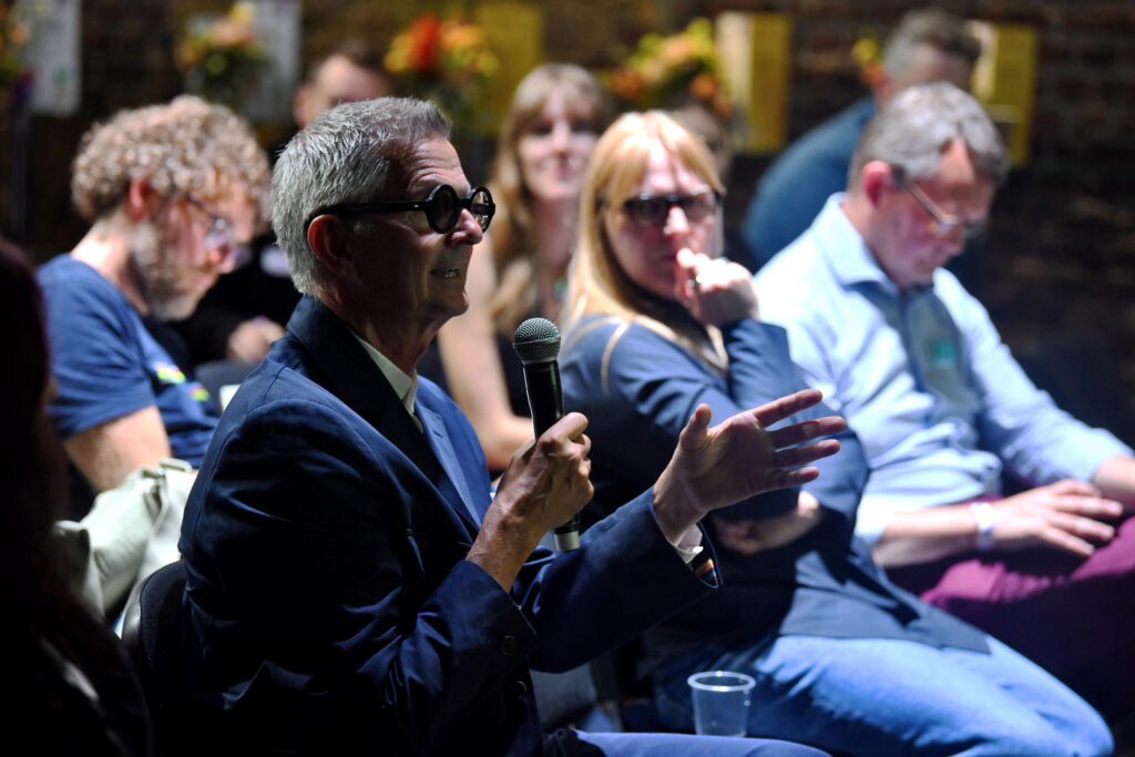 a man holding a microphone and speaking to a group of people