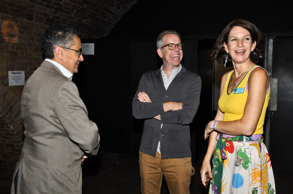 three people standing in a dark room talking