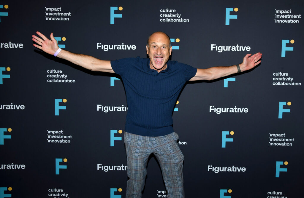 a man poses for a photo with his arms thrown wide