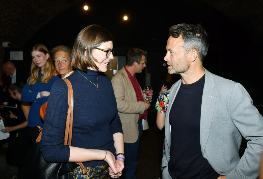 a man and woman talking in a busy, dark room